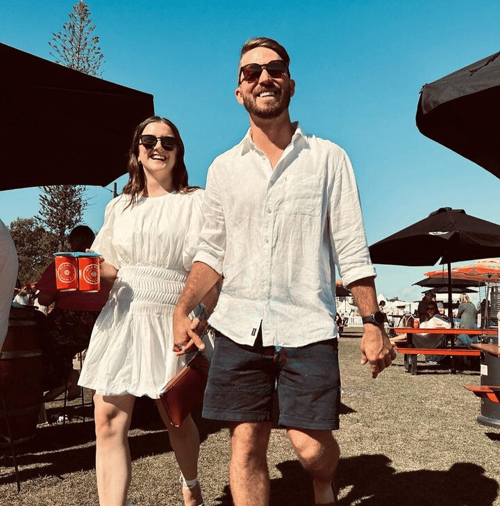 CarryMate environmentally friendly drink carrier, being used to carry two beer cans by happy couple at busy event