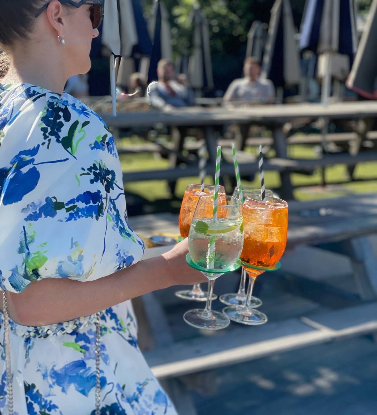 CarryMate environmentally friendly drink carrier, being used by woman to carry four cocktails in wine glasses